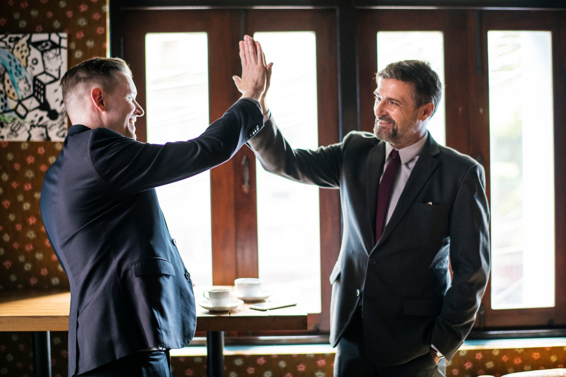 Two men in suits doing a high five. 